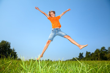 Boy jumping on the sunny meadow in a summer