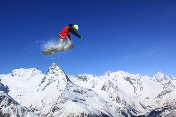 Flying snowboarder on mountains. Extreme sport.