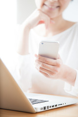 携帯電話でインターネットをする女性　ラップトップ　ノートパソコン
