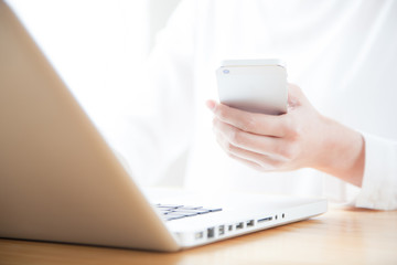 携帯電話でインターネットをする女性　ラップトップ　ノートパソコン
