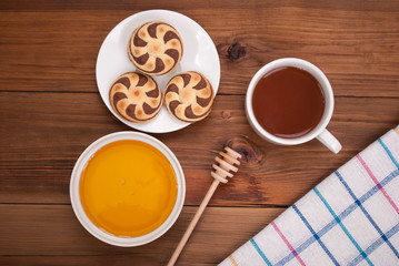 Cup of tea honey cookies on a wooden table.