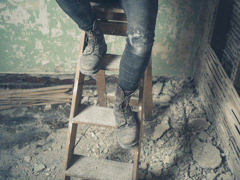 Legs of person sitting on stepladder
