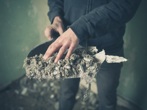 Hand with dustpan full of rubble