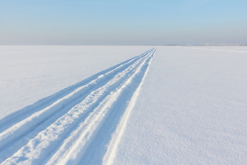 Traces from a snowmobile on a snow surface of the river