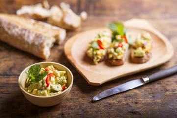 Avocado spread on slices of bruschetta against wooden table