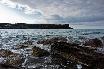 Sea rocks and waves at beach in San Pietro island, Sardinia, Italy
