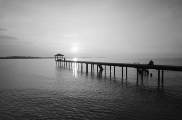 silhouette of a man sitting on the bridge alone in black and white