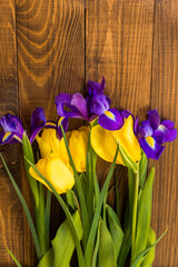 Close-up of beautiful tulips and irises on a dark wooden background
