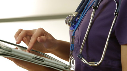 Close up of a young female nurse or doctor working with a digital tablet pc. - Powered by Adobe