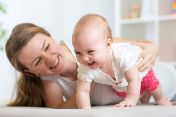 Obraz na płótnie Canvas Happy crawling baby girl with mother