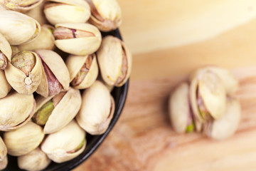 Closeup of a bowl of pistachios on wooden table