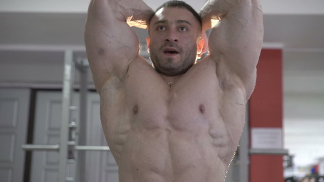 Muscular bodybuilder in gym posing on the camera. Slowly