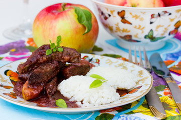 Liver with apples in red wine sauce with rice garnish. Useful and tasty dishes for lunch. Selective focus