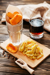 food, chicken nuggets and cola and fried potatoes on a wooden background