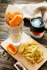food, chicken nuggets and cola and fried potatoes on a wooden background