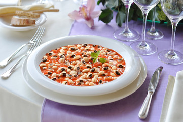 Plate of beans with tomatoes on laid table