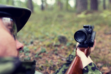 Obraz premium close up of soldier or hunter with gun in forest