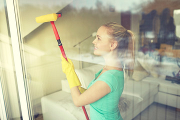 happy woman in gloves cleaning window with sponge