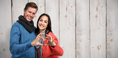 Composite image of portrait of couple making heart shape