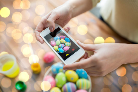close up of hands with easter eggs and smartphone