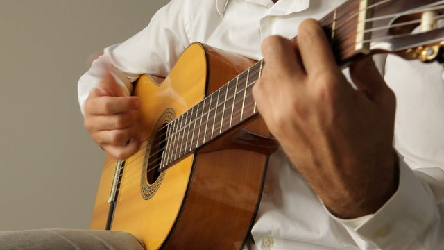 Hands playing a spanish guitar seen from the guitar headstock