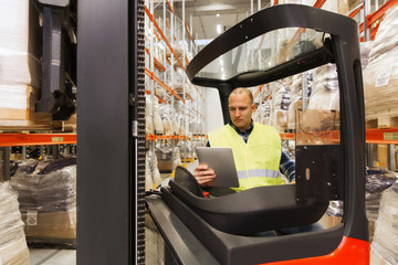 man with tablet pc operating forklift at warehouse