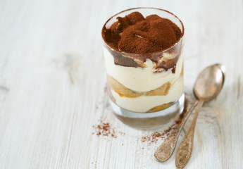 tiramisu in glass on wooden surface