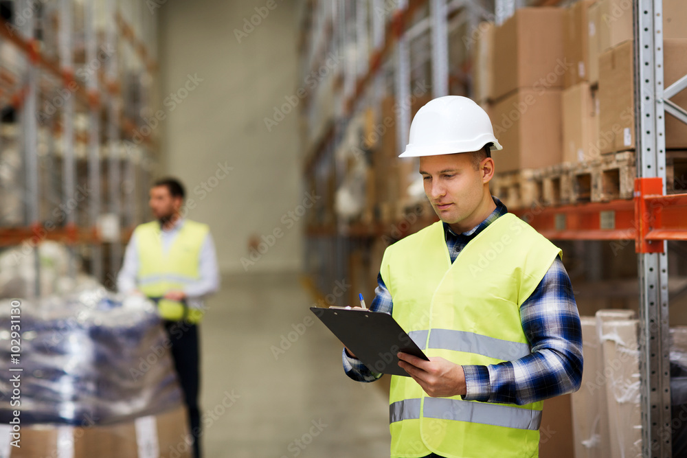 Sticker man with clipboard in safety vest at warehouse