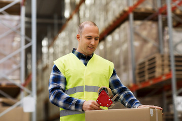 man in safety vest packing box at warehouse