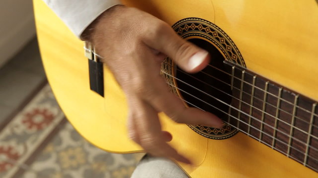 Hand strumming guitar strings seen from a high angle view