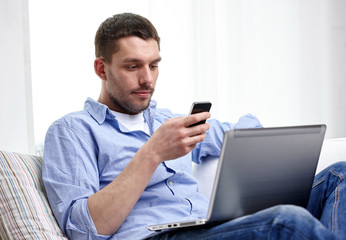 man with smartphon and laptop computer at home