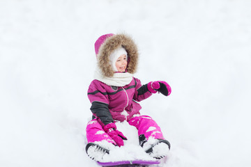Fototapeta na wymiar happy little kid on sled outdoors in winter