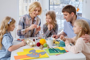 Cheerful family having fun painting and decorating easter eggs.