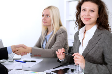 A group of business people at a meeting on the background of office. Business handshake. Focus on a beautiful blonde