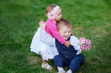 Little girl hugging a boy with a bouquet of flowers in park