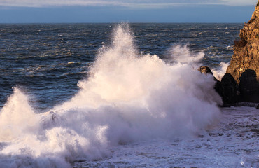 wave crashing over rock with sunset light