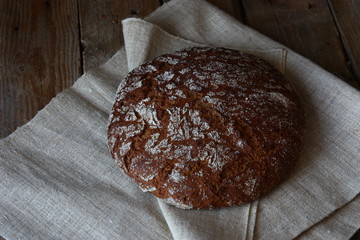 Whole black bread on wooden table close-up