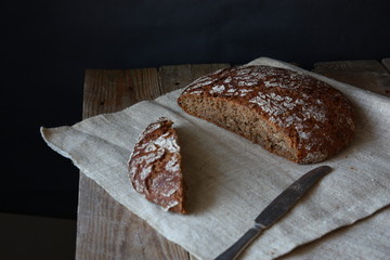 Whole black bread on wooden table close-up