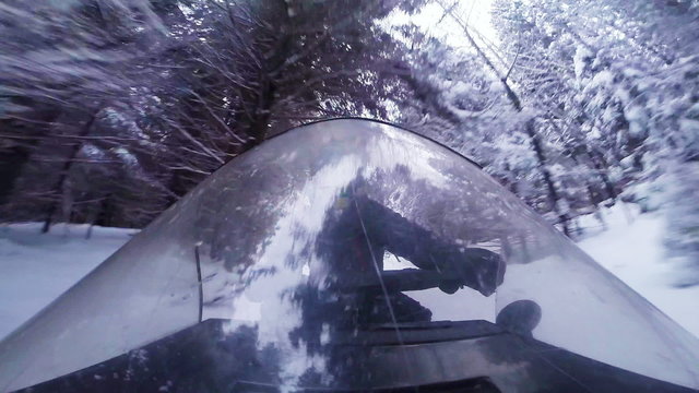 Fast Snowmobile Driver and Windshield Reflection in a Forest Path