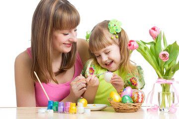 Obraz na płótnie Canvas happy mother and child daughter preparing to easter holiday and with brush coloring eggs