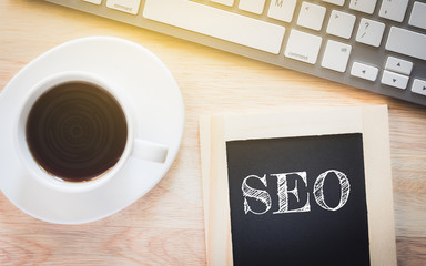 Concept SEO message on wood boards. A keyboard and a glass coffee table.Vintage tone.