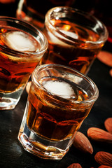Cold whiskey with ice in a glass and a snack almonds, selective