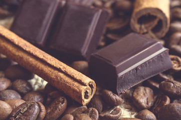 Close-up of cinnamon sticks, chocolate blocks on coffee beans.