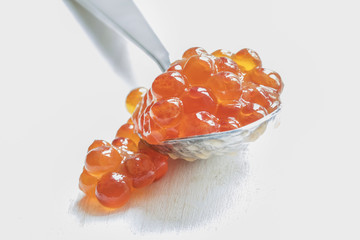 Red caviar in the silver spoon on a white background, selective