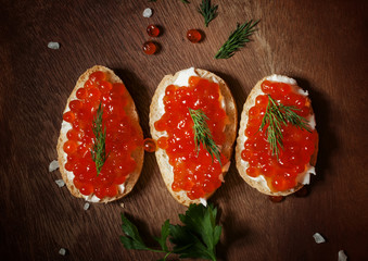 Sandwiches with red caviar and butter on a wooden cutting board,