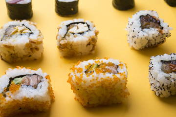 Various kinds of sushi food served on yellow blackground