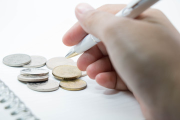coins on book and hand holding pen business finance home concept