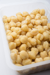 a plastic jar with cooked chickpeas on a white background