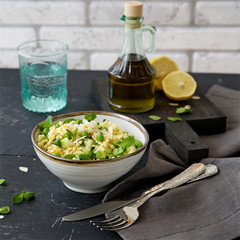 Pasta salad (fregola) with green peas, cucumber, lemon and mint in the bowl 
 