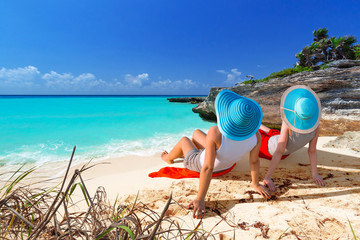 Fototapeta na wymiar Two women with hats enjoying sun holidays on the tropical beach